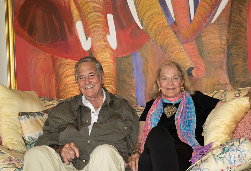 Jim, and his wife, Betsey, an amazing wildlife artist. She painted the incredible elephant painting behind them